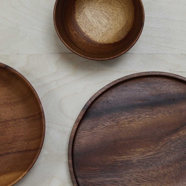Drei handgefertigte Holzschalen in unterschiedlichen Größen auf einer hellen Holzoberfläche.